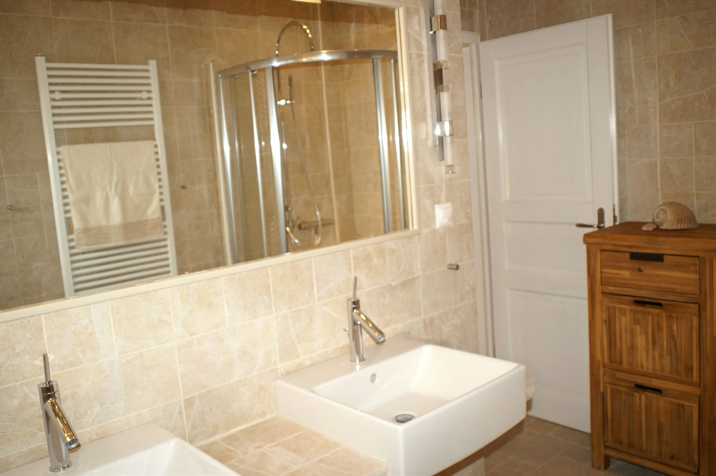 Das zweite Badezimmer überzeugt ebenfalls durch edle Natursteinfliesen und moderne Sanitäreinrichtungen. Es ist mit einer großzügigen Dusche und einem Doppelwaschbecken ausgestattet.