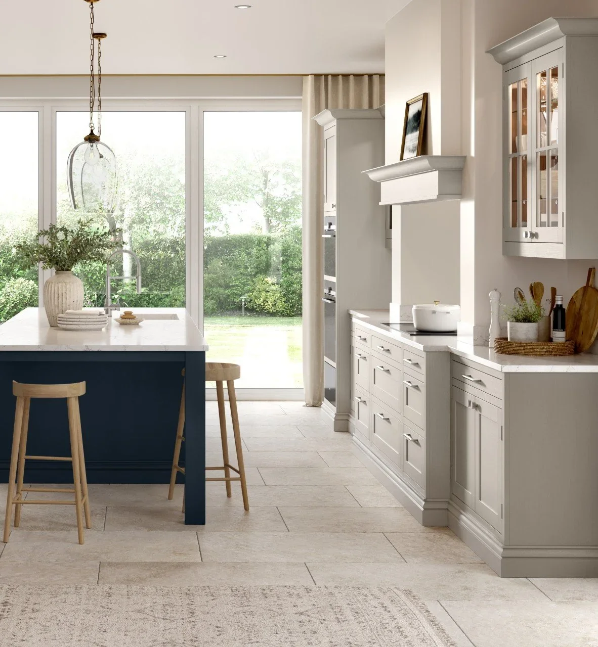 Modern kitchen with white cabinets, marble countertops, and a central island. Large windows provide natural light. Features bar stools, a hanging light fixture, and decorative plants.
