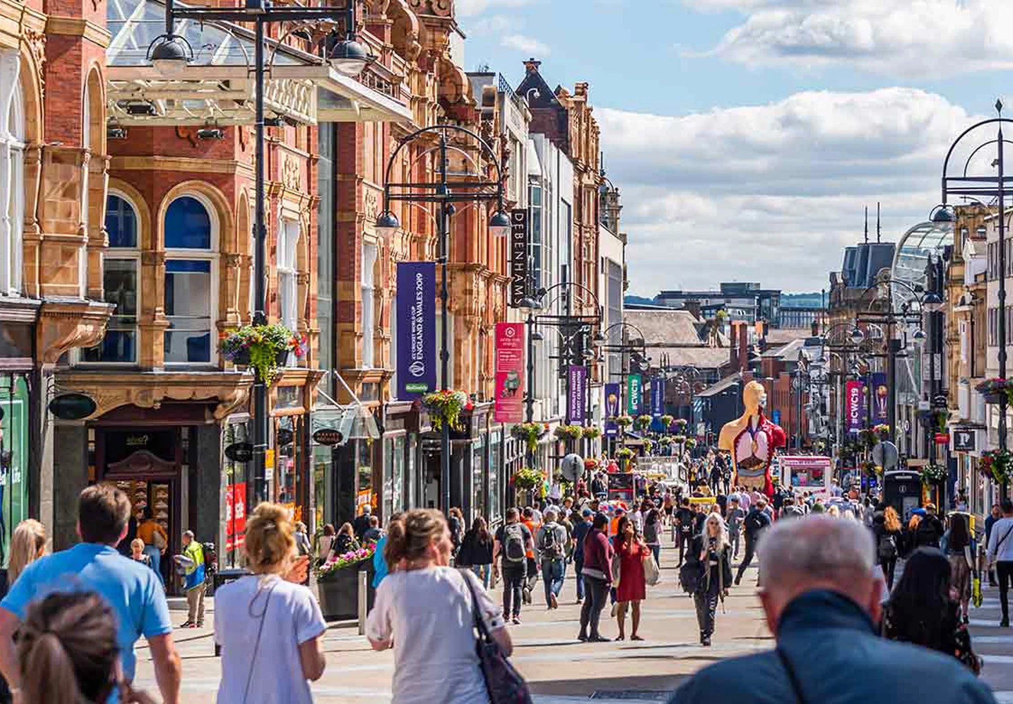 Shoppers walking on Briggate in Leeds in the sun
