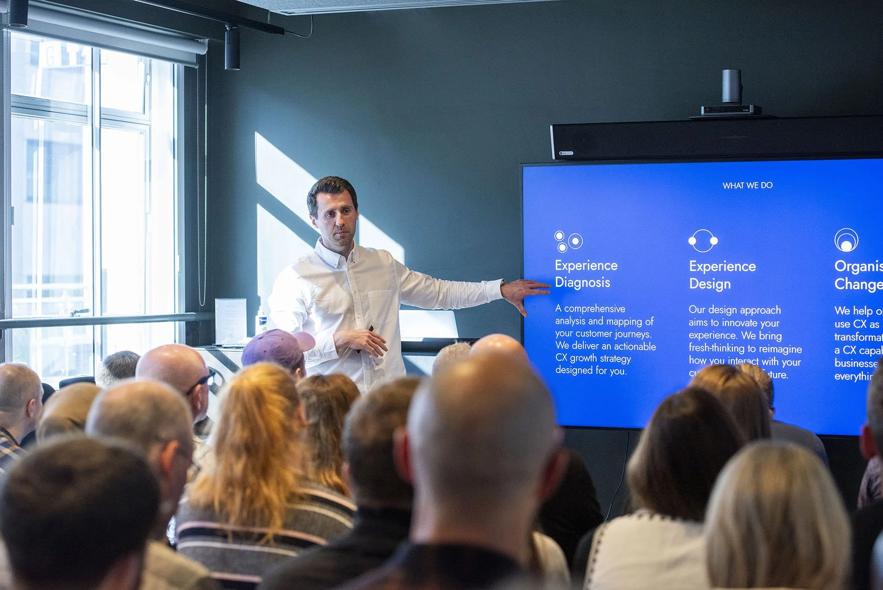 A photo of AAWE founder, Tom Belt speaking to a crowded room at an event.