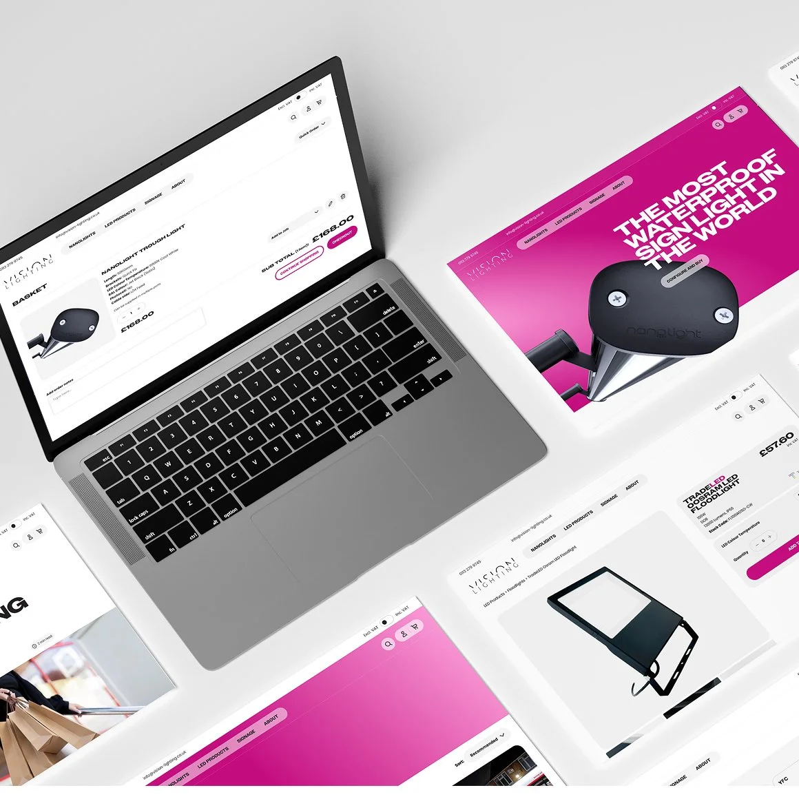 Open laptop on a white surface surrounded by marketing material for a lighting product, featuring pink and white graphics and a black lighting device.