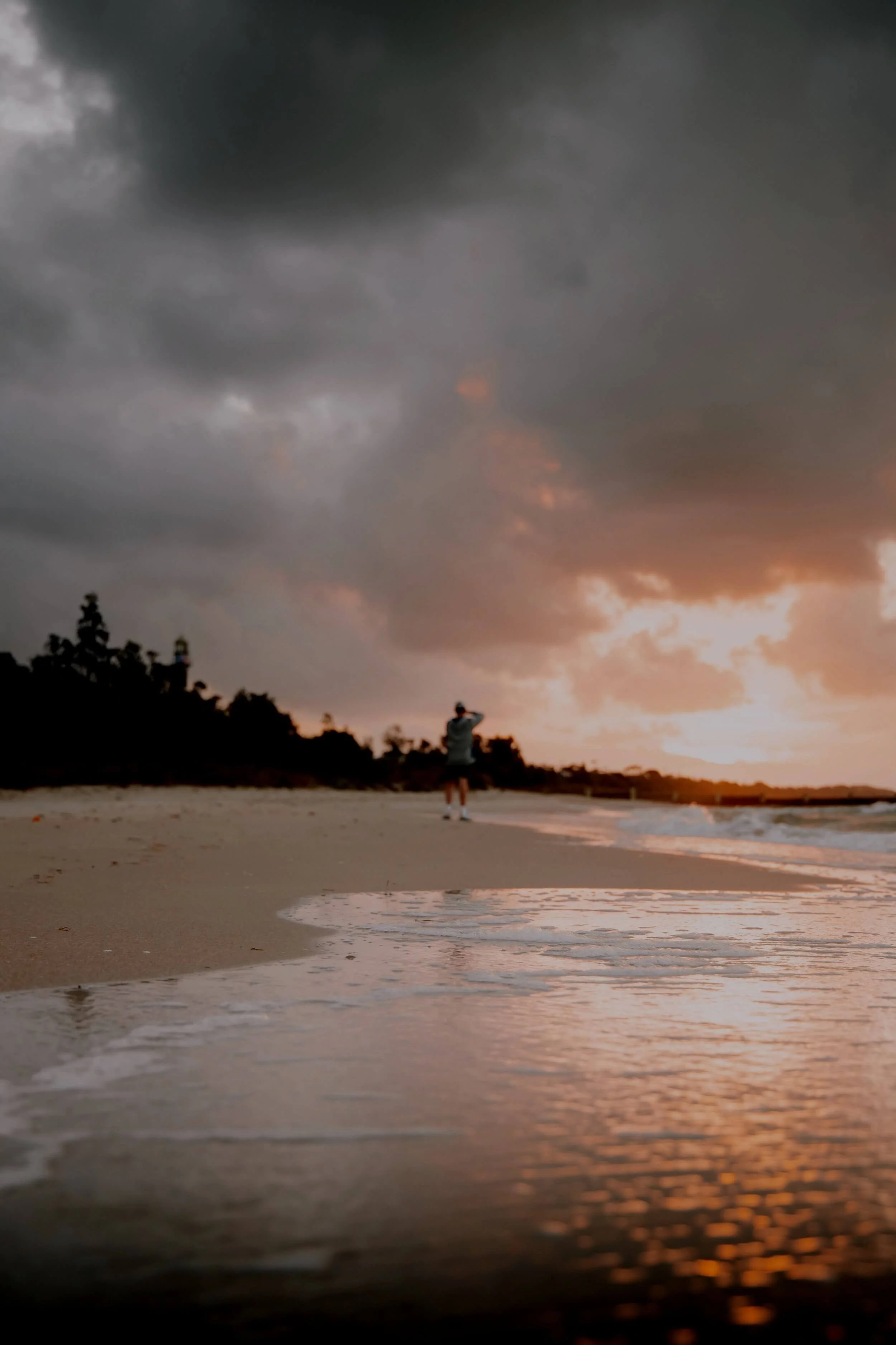 Person walking alone along a beach at sunset under dark clouds, representing recovery after being injured in a public place