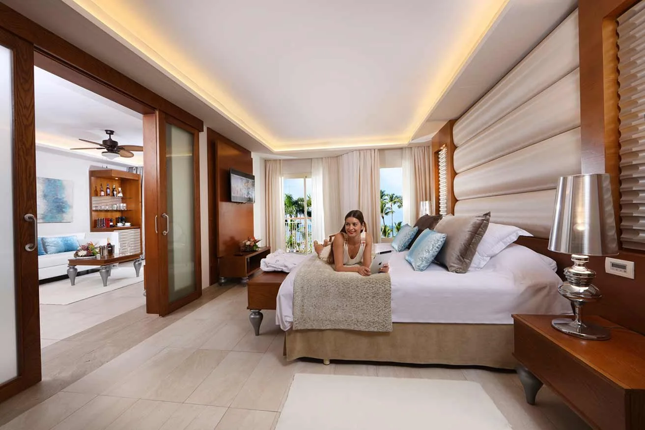 Family-Club-One-Bedroom-Suite-bed-woman.jpg