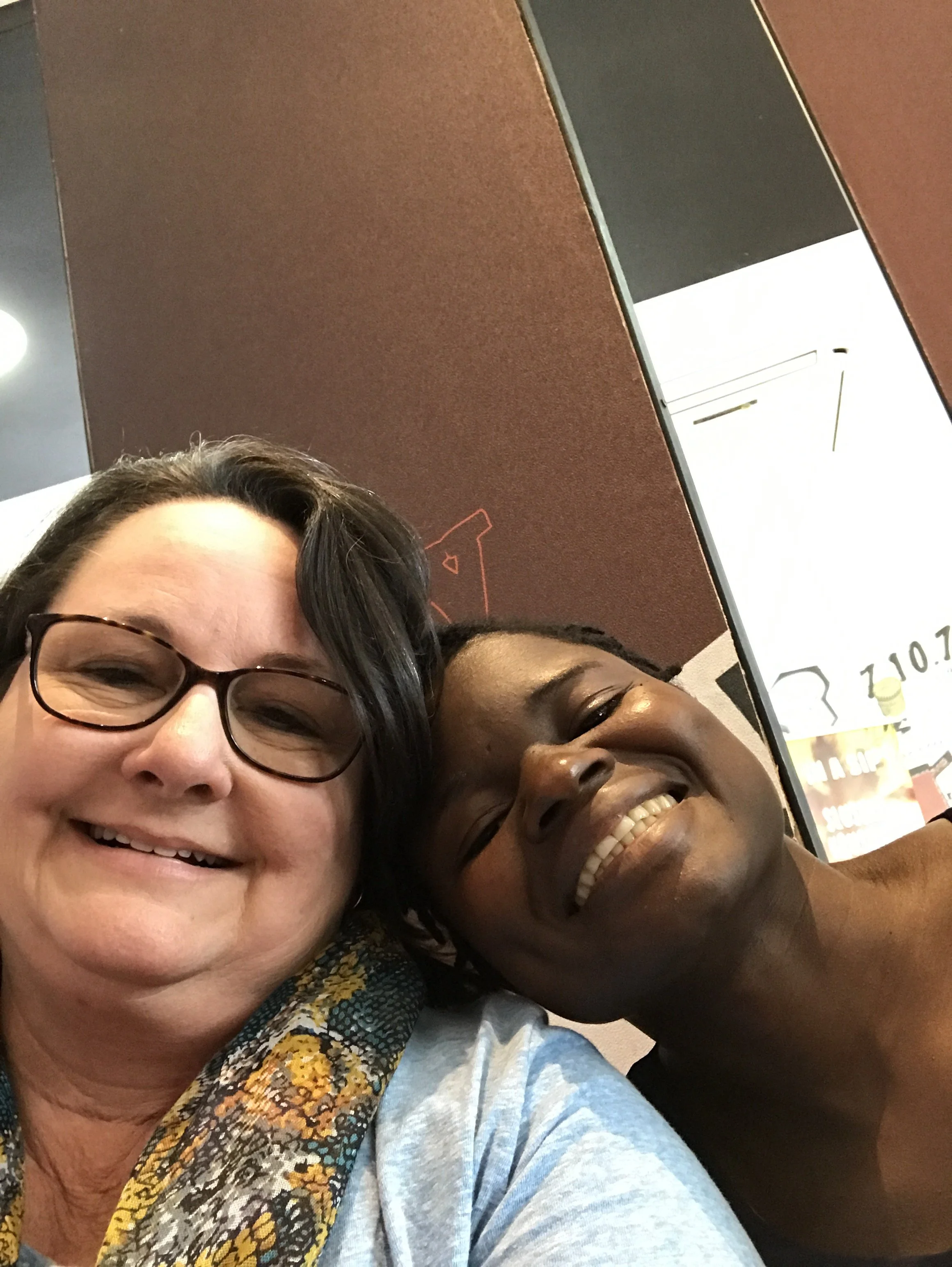 Close-up of three smiling women taking a selfie together in an indoor setting.