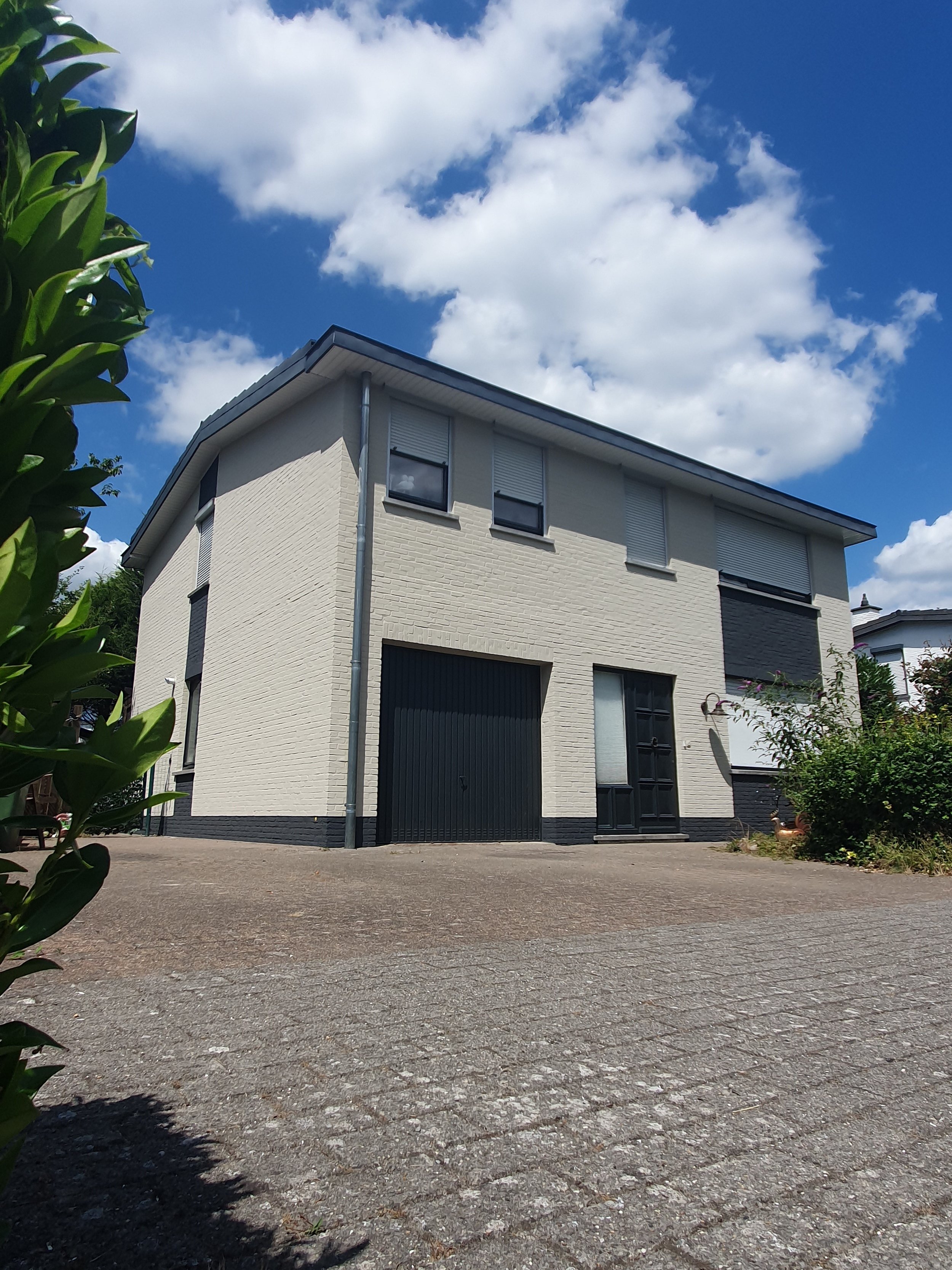 Buitenschilderwerk: vrijstaande woning met licht geschilderde gevel en donkere plint