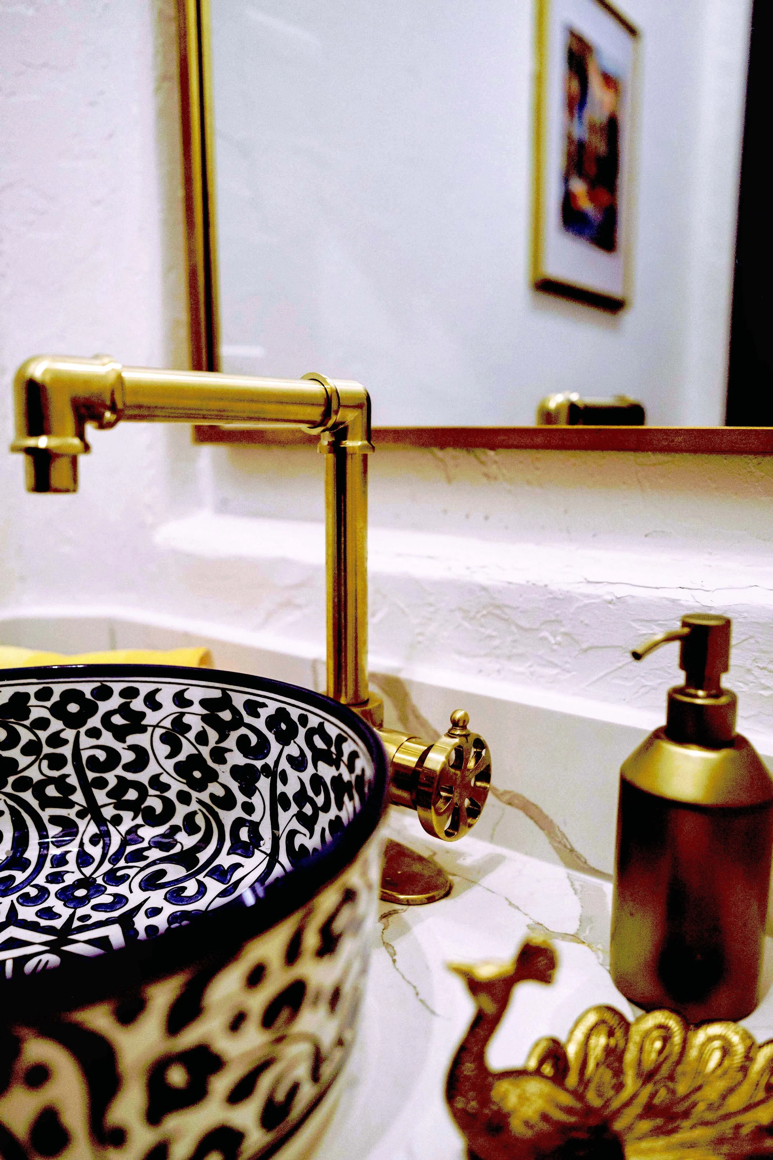 A brass faucet fashioned in the form of a traditional tap is paired with the vessel sink.