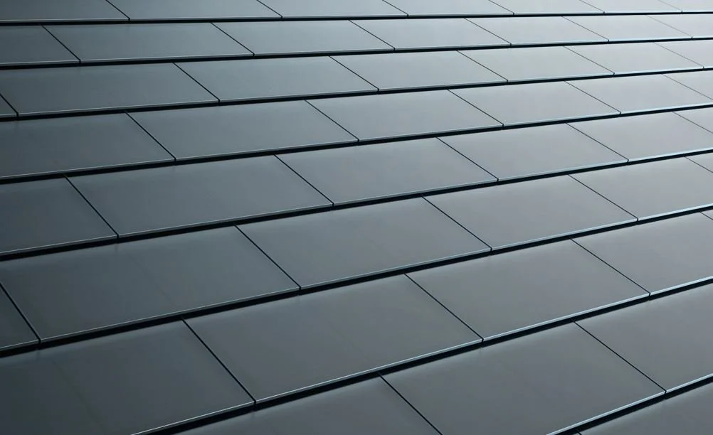Modern roof featuring uniform dark solar tiles arranged across the surface for a clean, streamlined appearance.