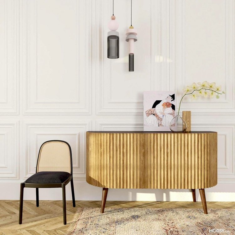 Sophisticated living space with a fluted wooden credenza, cane-back chair, pendant lights, and decorative accents.