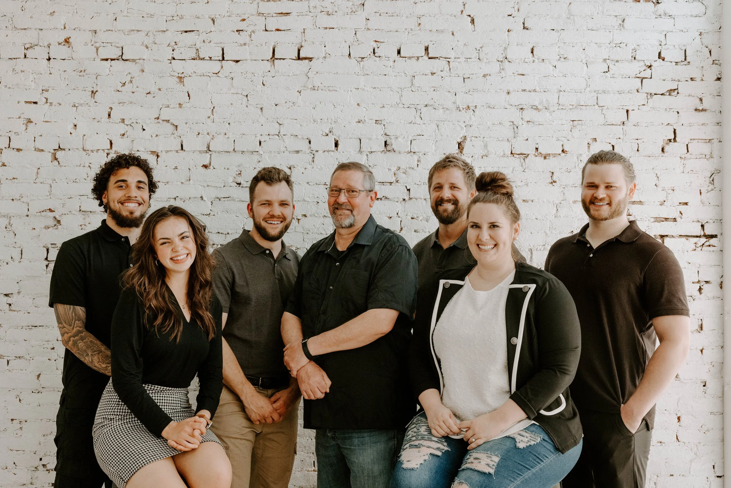Vatter Construction design-build team posing together in Lancaster, PA, against a textured white brick wall.
