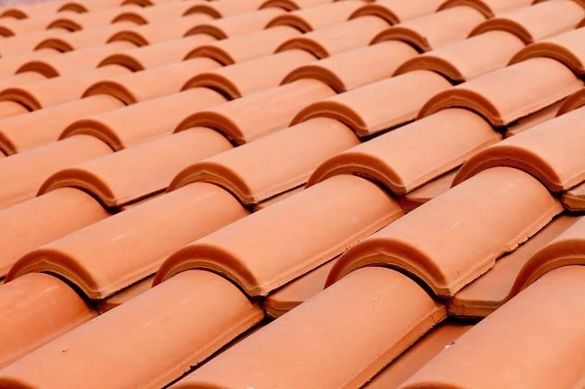 Close-up of traditional clay roofing material featuring rows of durable-looking terracotta tiles in an interlocking design.
