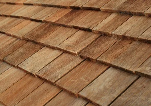 Close-up texture of overlapping natural wooden roof shingles and shakes.