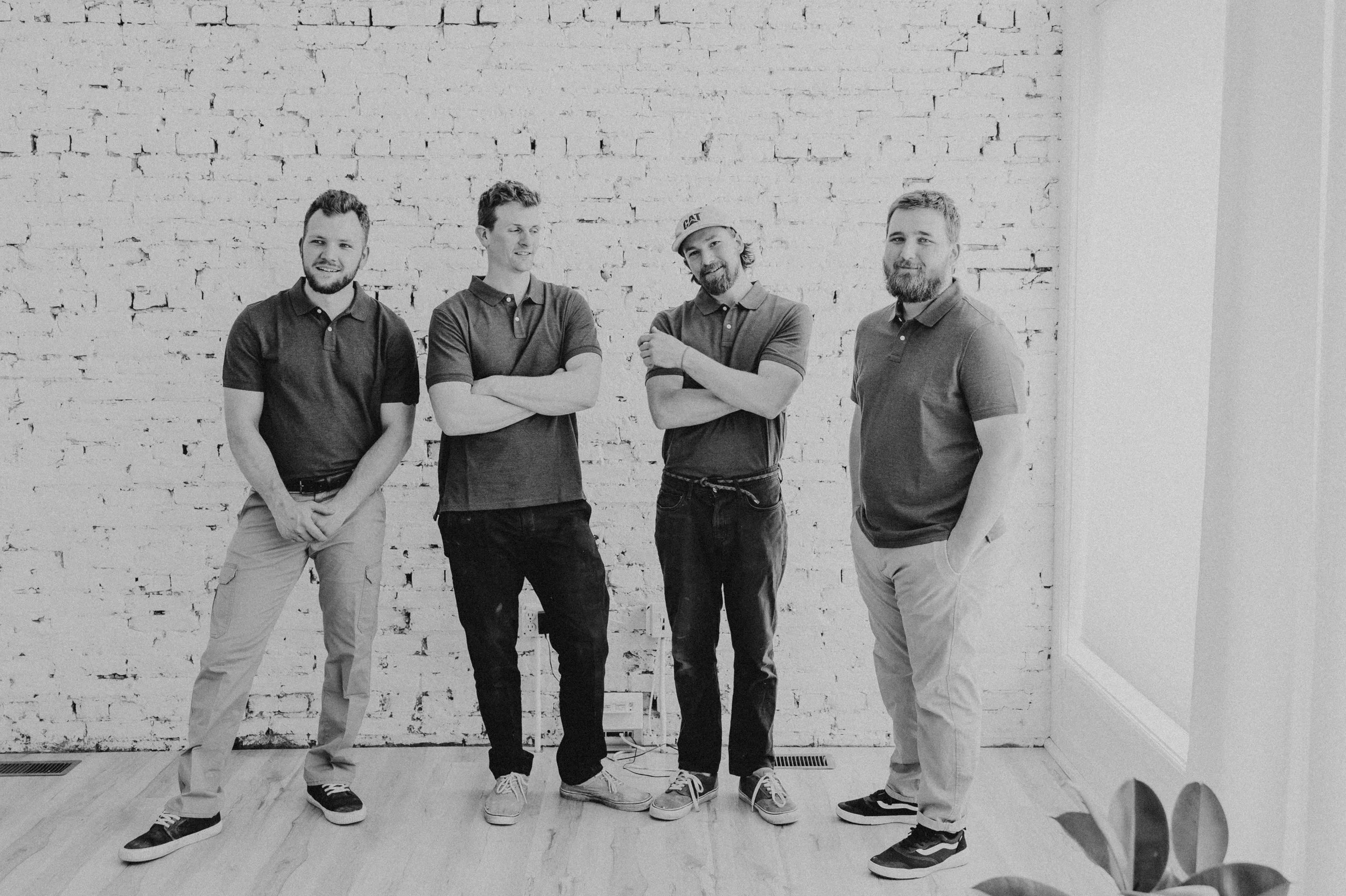 Vatter Construction field team standing together in front of a white brick wall.