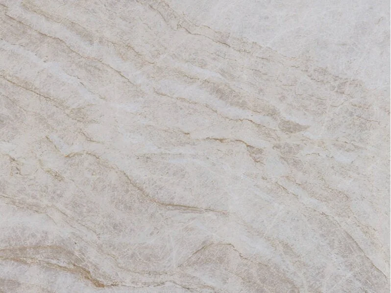 Taj Mahal Quartzite surface featuring warm neutral tones, flowing diagonal veins, and a smooth polished finish for architectural applications.
