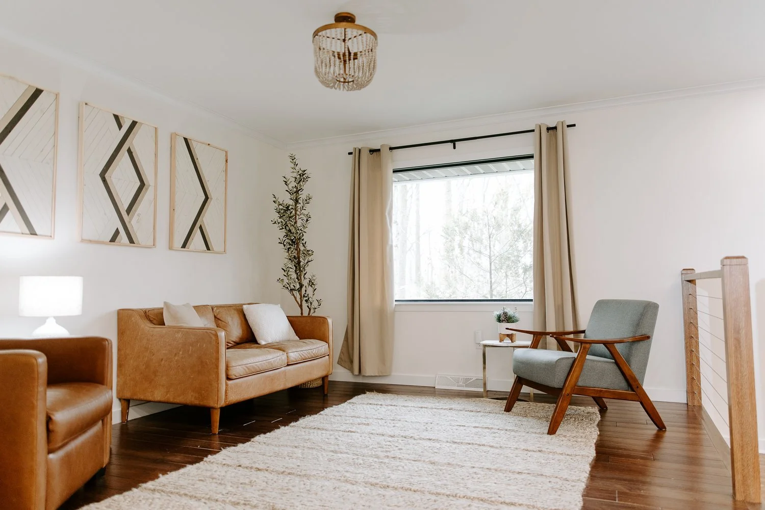 Hardwood flooring in a cozy living room with a textured area rug, leather seating, geometric wall art, and neutral décor.
