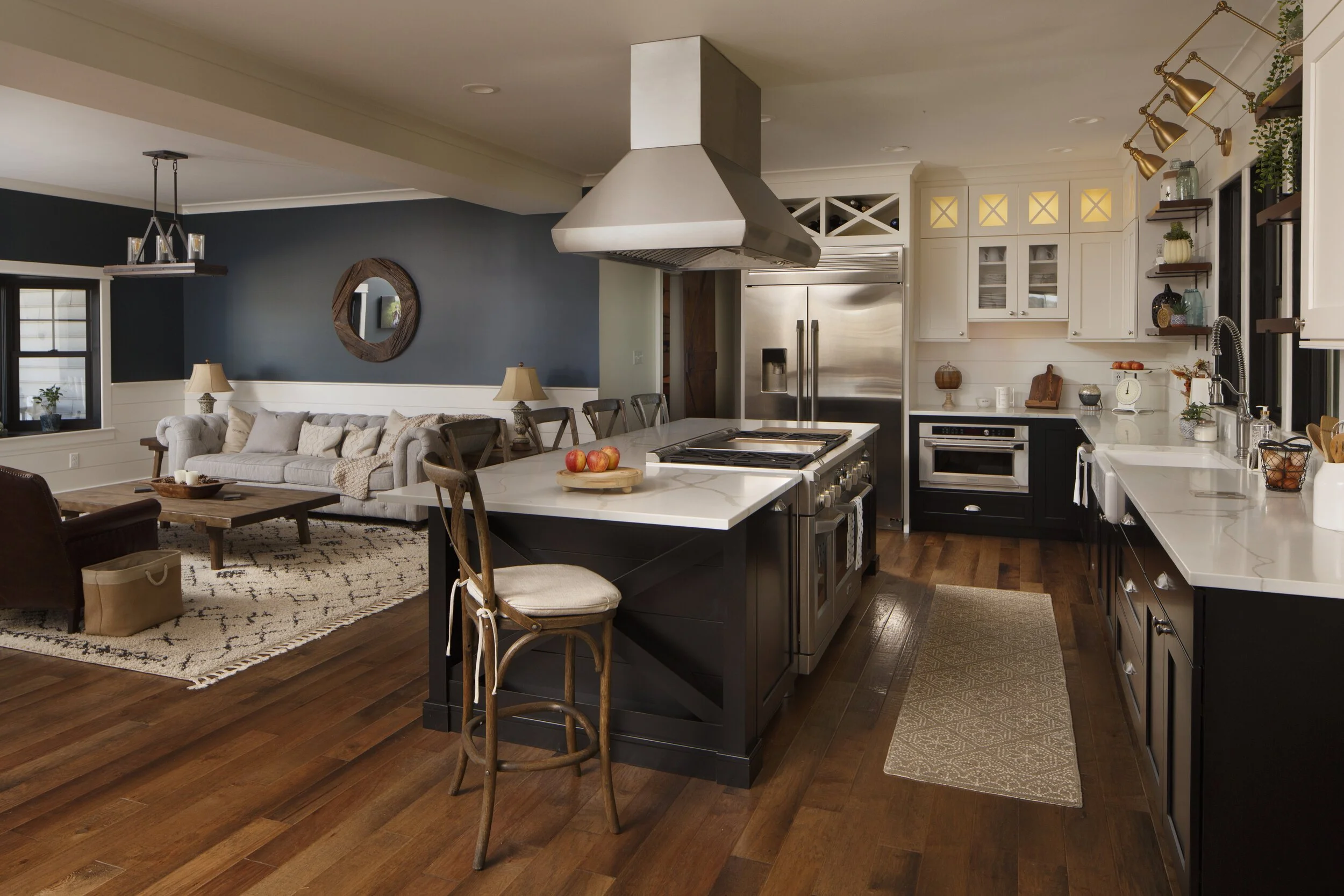 Spacious open-concept interior connecting a kitchen with a dark island and white quartz countertop to a living room with a gray sofa.