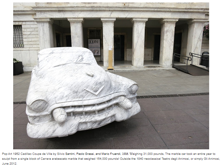 Life-sized sculpture of a classic Cadillac carved from Carrara arabescato marble displayed outside a historic building