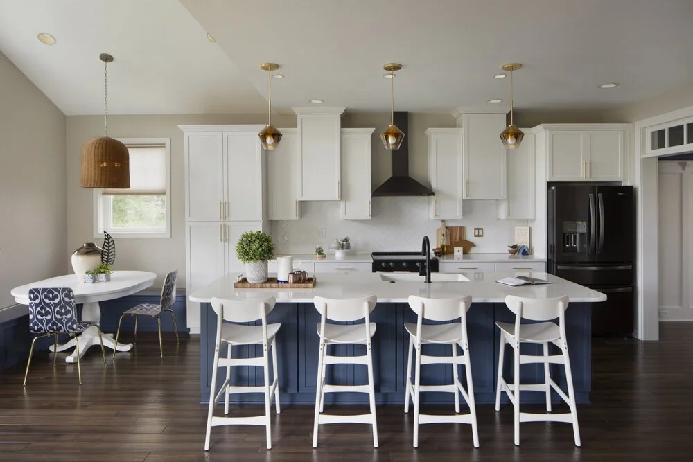 Modern kitchen with a deep blue island, white quartz countertop, four white barstools, and matching white perimeter cabinetry.