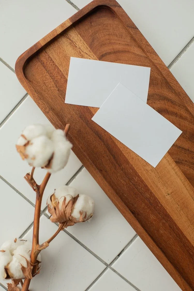White square tile flooring with visible grout lines beneath a wooden tray and dried cotton branch.