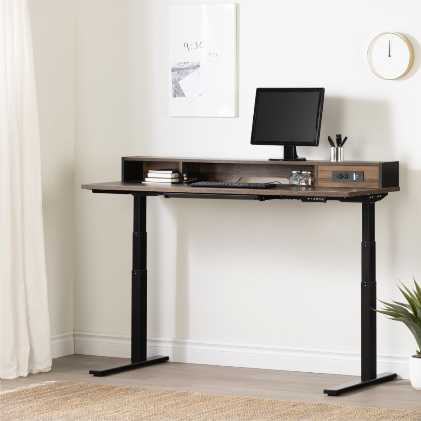 Organized home office with an adjustable standing desk, mounted memo board, monitor, and built-in storage for remote work.