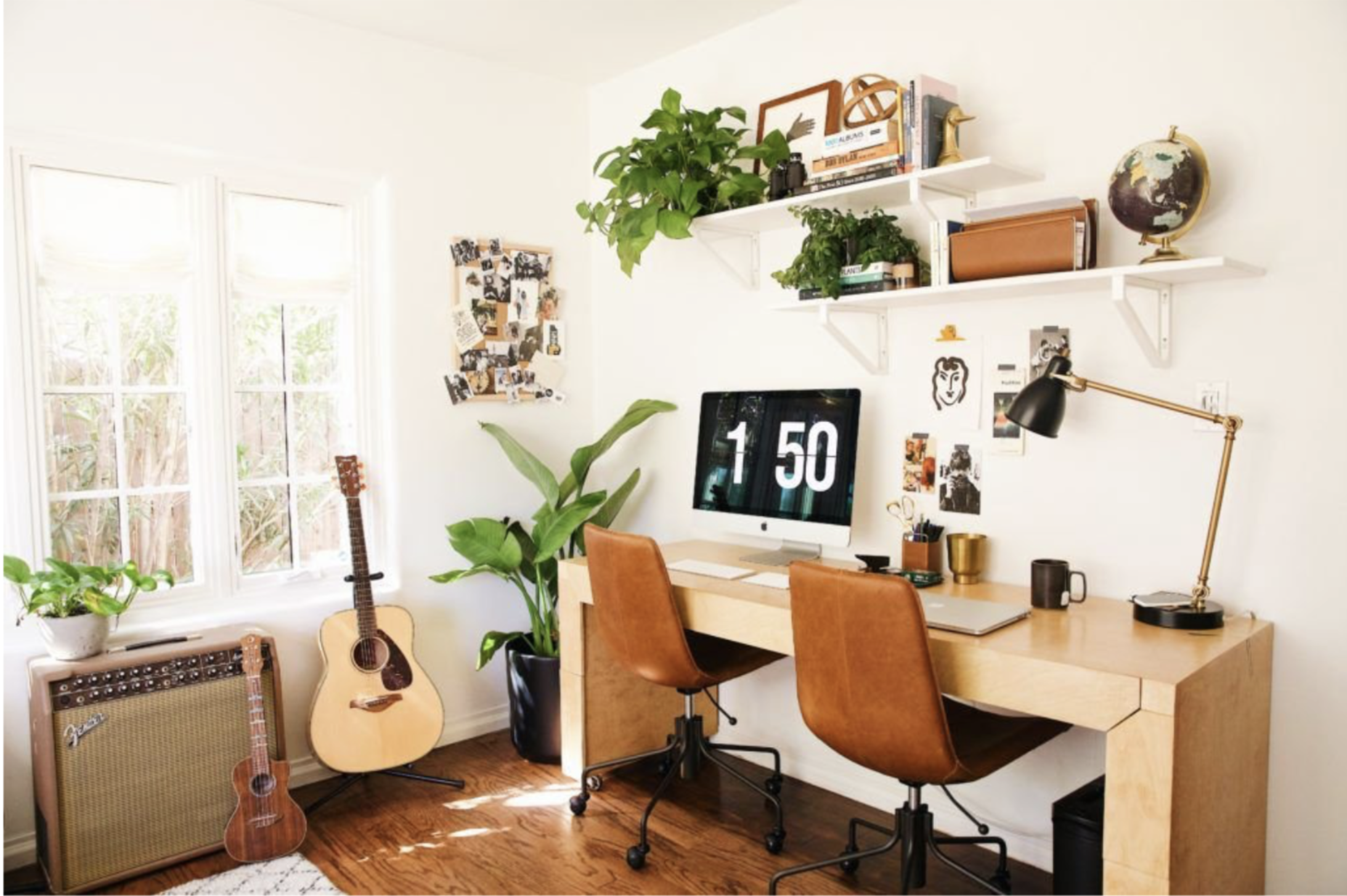 Personalized home office featuring two desks, leather chairs, a brass desk lamp, wall decor, and bright corner windows.