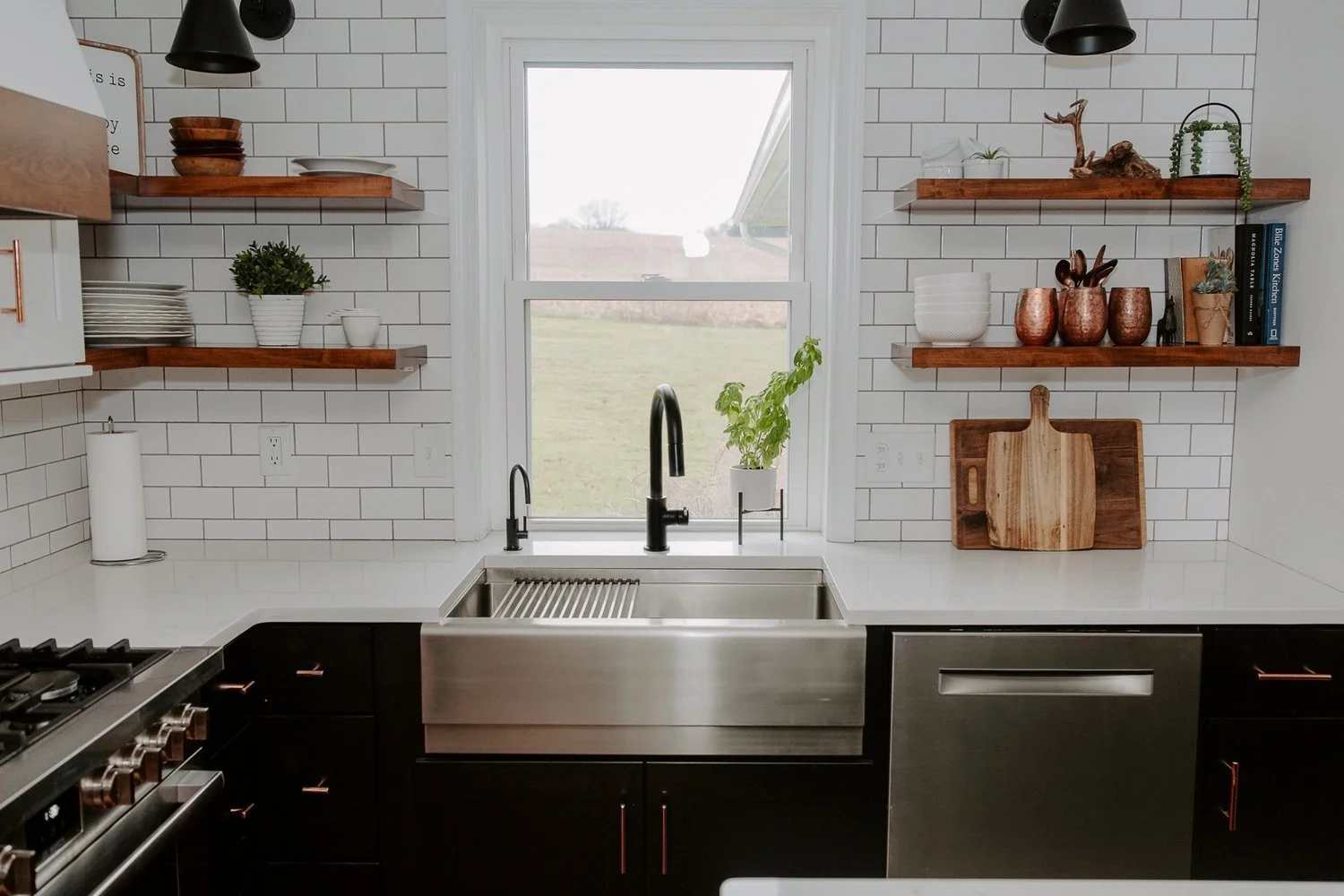 Kitchen remodeling project featuring a stainless steel farmhouse sink, white quartz countertop, subway tile backsplash, and floating wood shelves.