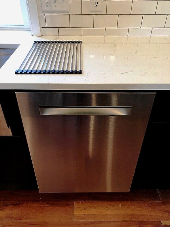 Polished quartz countertop with subtle gray veining installed above a stainless steel dishwasher in a modern kitchen.