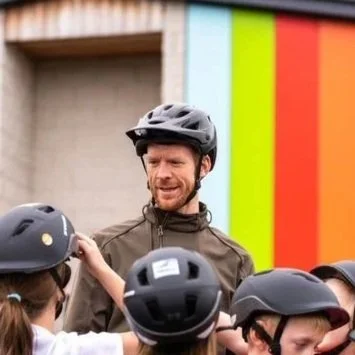 Ed Clancy wearing a helmet with school children wearing helmets in the foreground