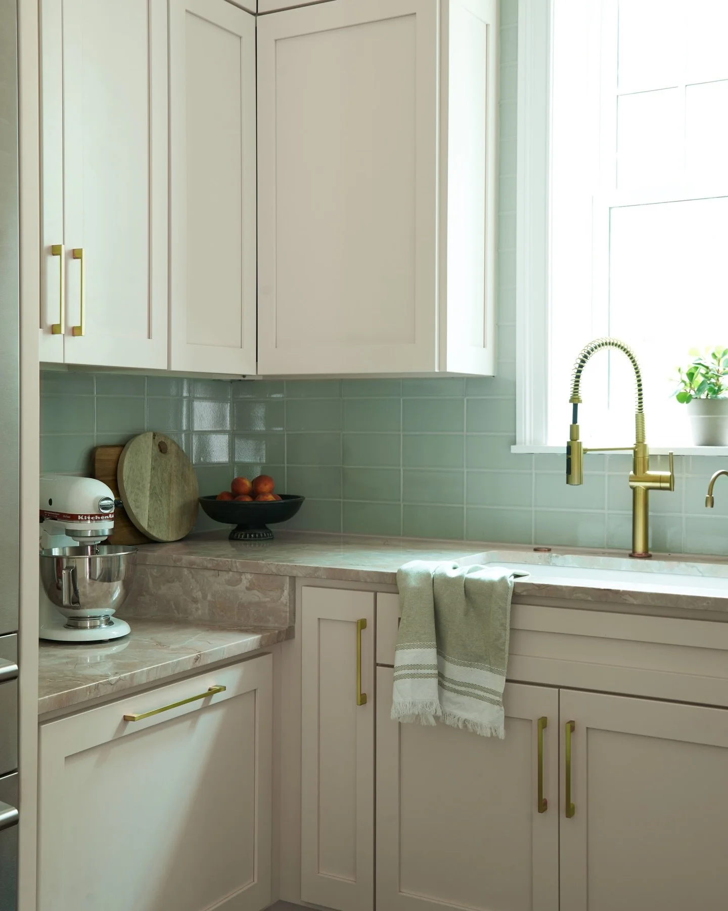 A subtle color contrast even in a neutral kitchen goes a long way. It keeps the space feeling timeless without tipping into stark or flat.

Instead of going fully monochromatic, we switched things up here! Warming this corner with soft green tile and