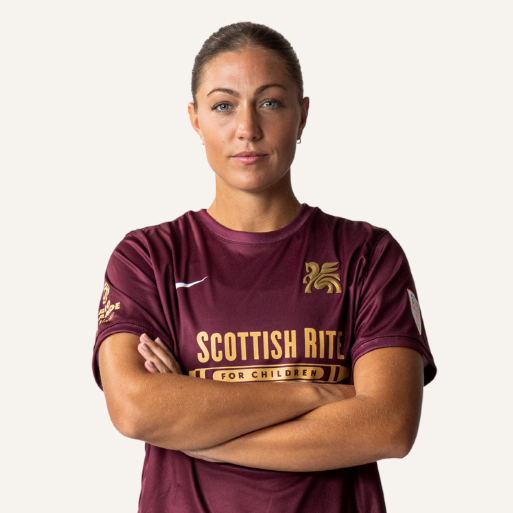 A woman in a sports jersey with arms crossed.