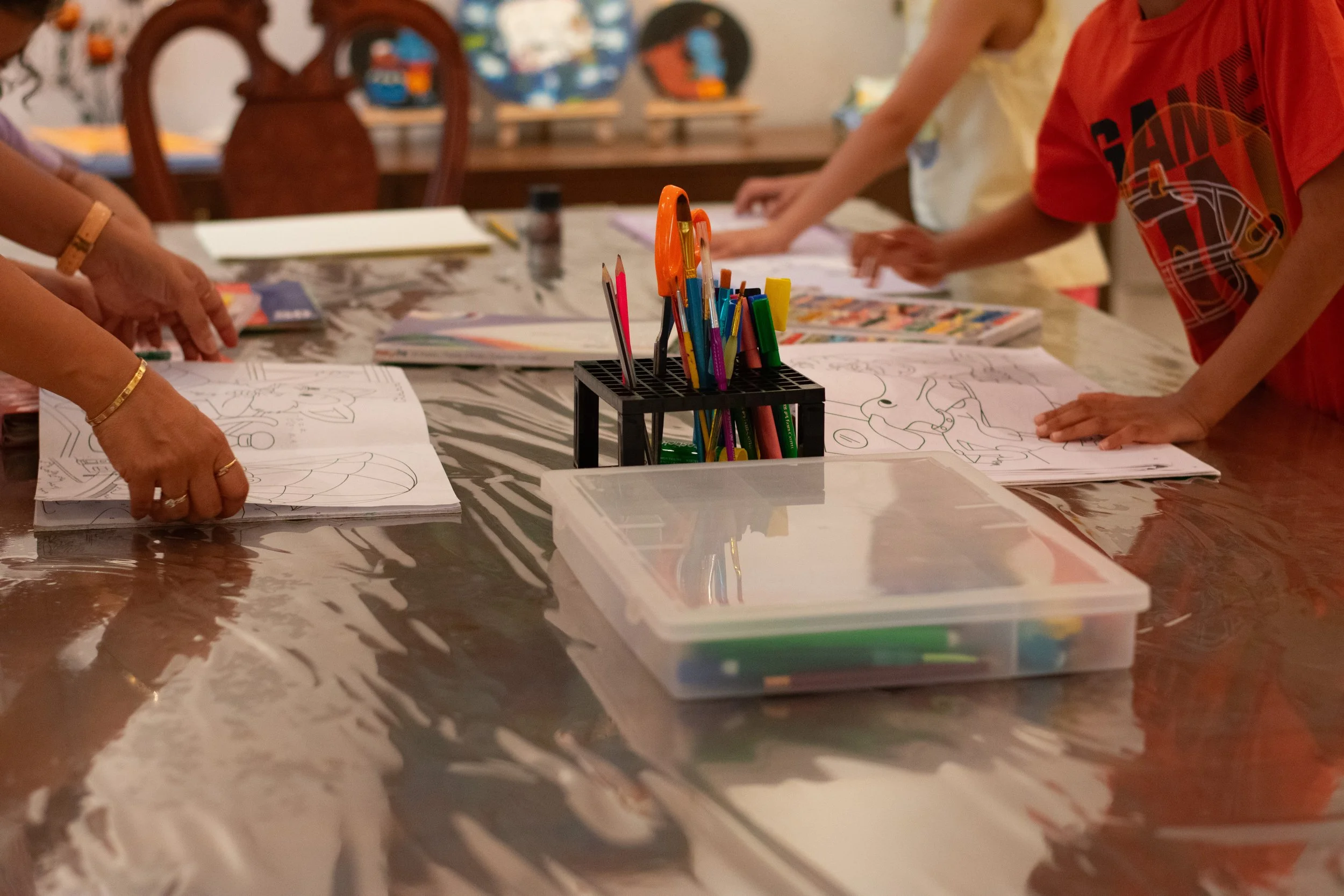 Children's coloring books and drawings on a table with various colored markers and pencils