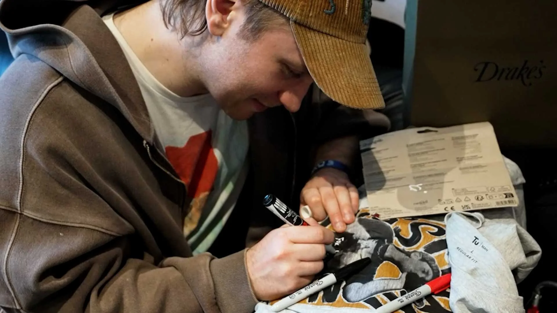 A person with a backpack and outdoor gear standing outside a brick building with a sign that says 'ENTREE'.