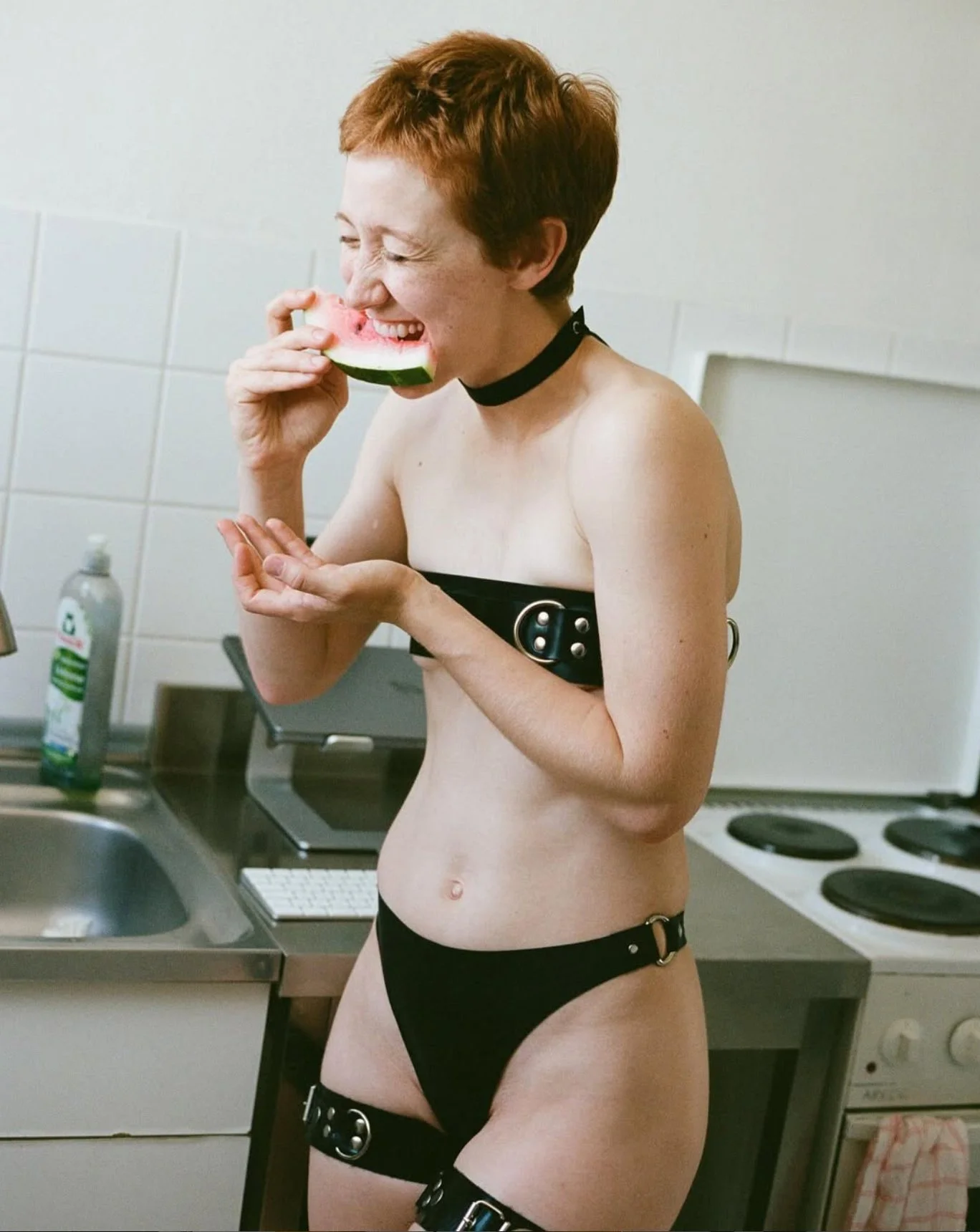 Kink girl eating a melon in a kitchen