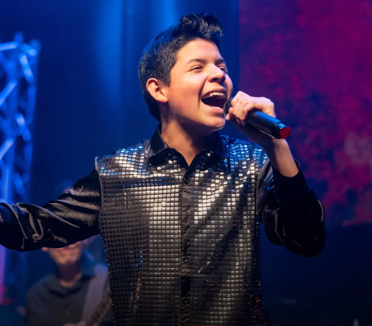 Young singer performing live on stage with a band