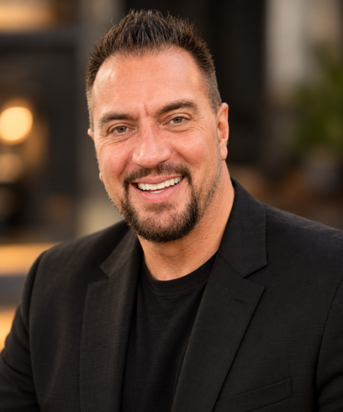 Caleb Chapman, a smiling man with a dark beard, wearing a black jacket and black shirt.