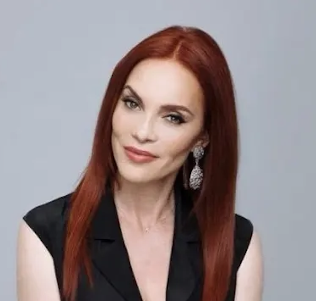 Carmit Bachar, a woman with long red hair wearing a black top.