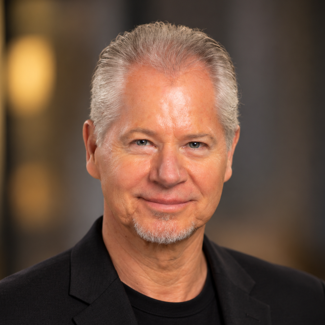 Mark Blosil, a smiling man with gray hair and a goatee, wearing a black jacket and black shirt.