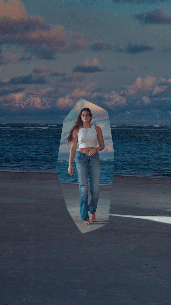 Woman walking on beach with jeans and a tank top, surrounded by surreal effect.