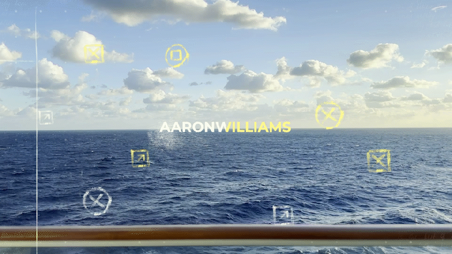 View of ocean and sky from ship's deck with text "AARON WILLIAMS" overlaid, featuring a railing and digital graphics.