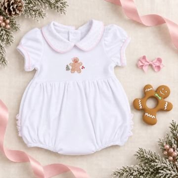 White baby romper with embroidered gingerbread man detail surround by festive decor