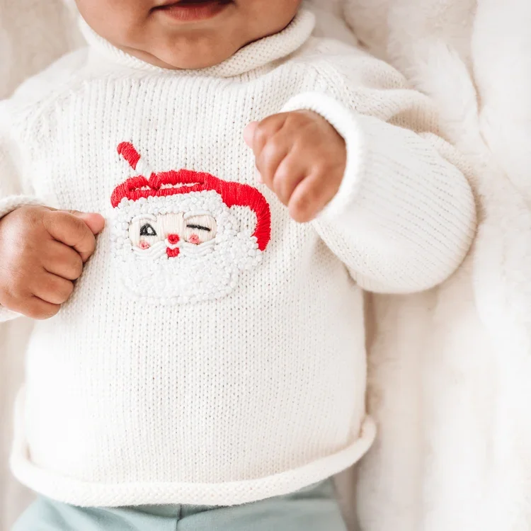 Ivory pullover sweater with appliqued santa mug on a baby
