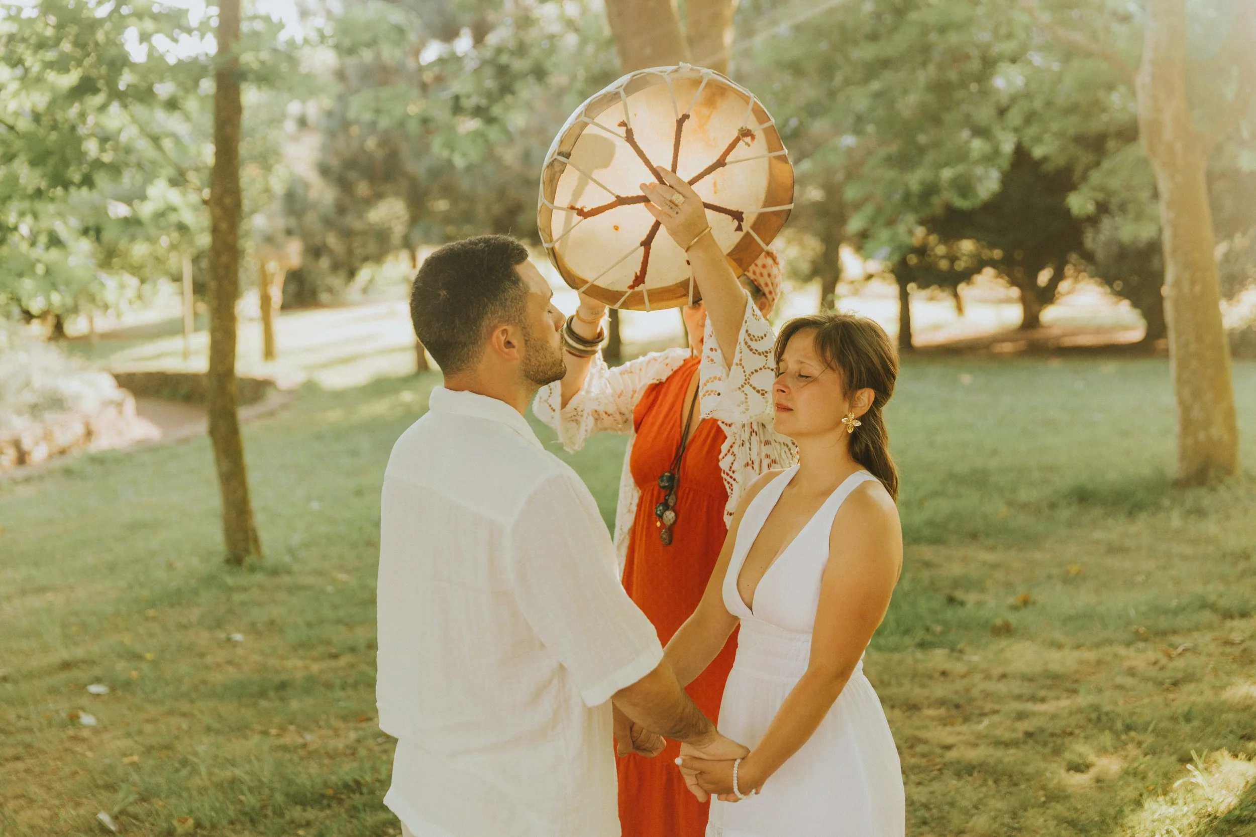 Casal de noivos segurando as mãos e um dragão de papel durante um casamento ao ar livre.