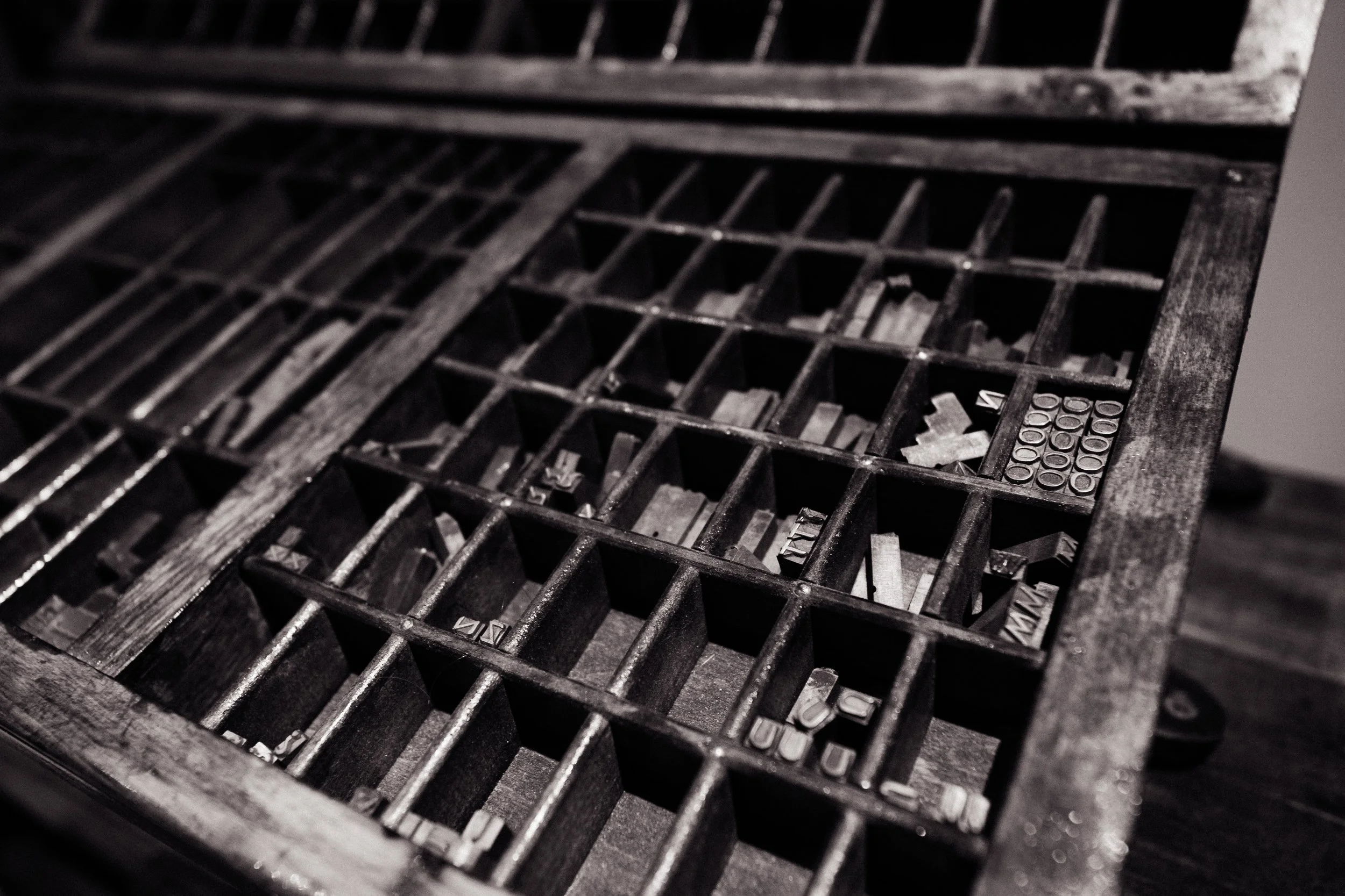 Close-up view of an old, black metal casket with compartments and slots, seen at an angle.