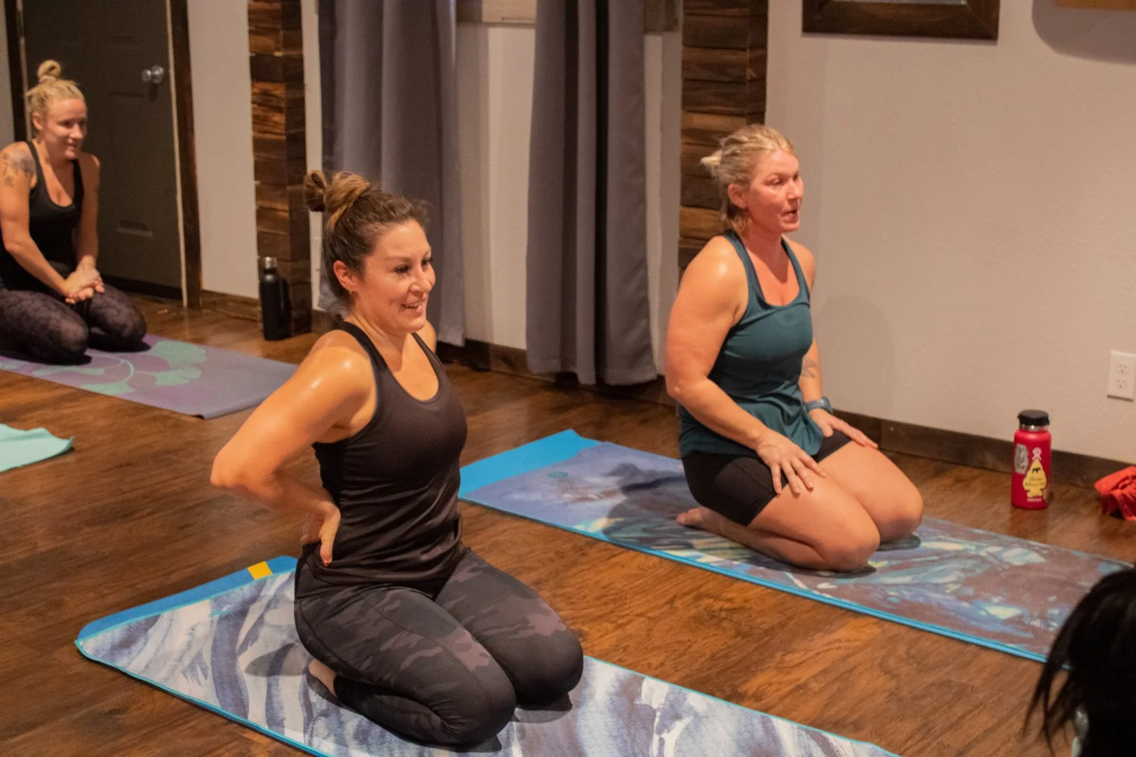 A photo of two Black Horse Yoga members smiling on their yoga mats.