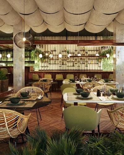 Interior of a modern restaurant with green chairs, wooden floors, and tropical plants.