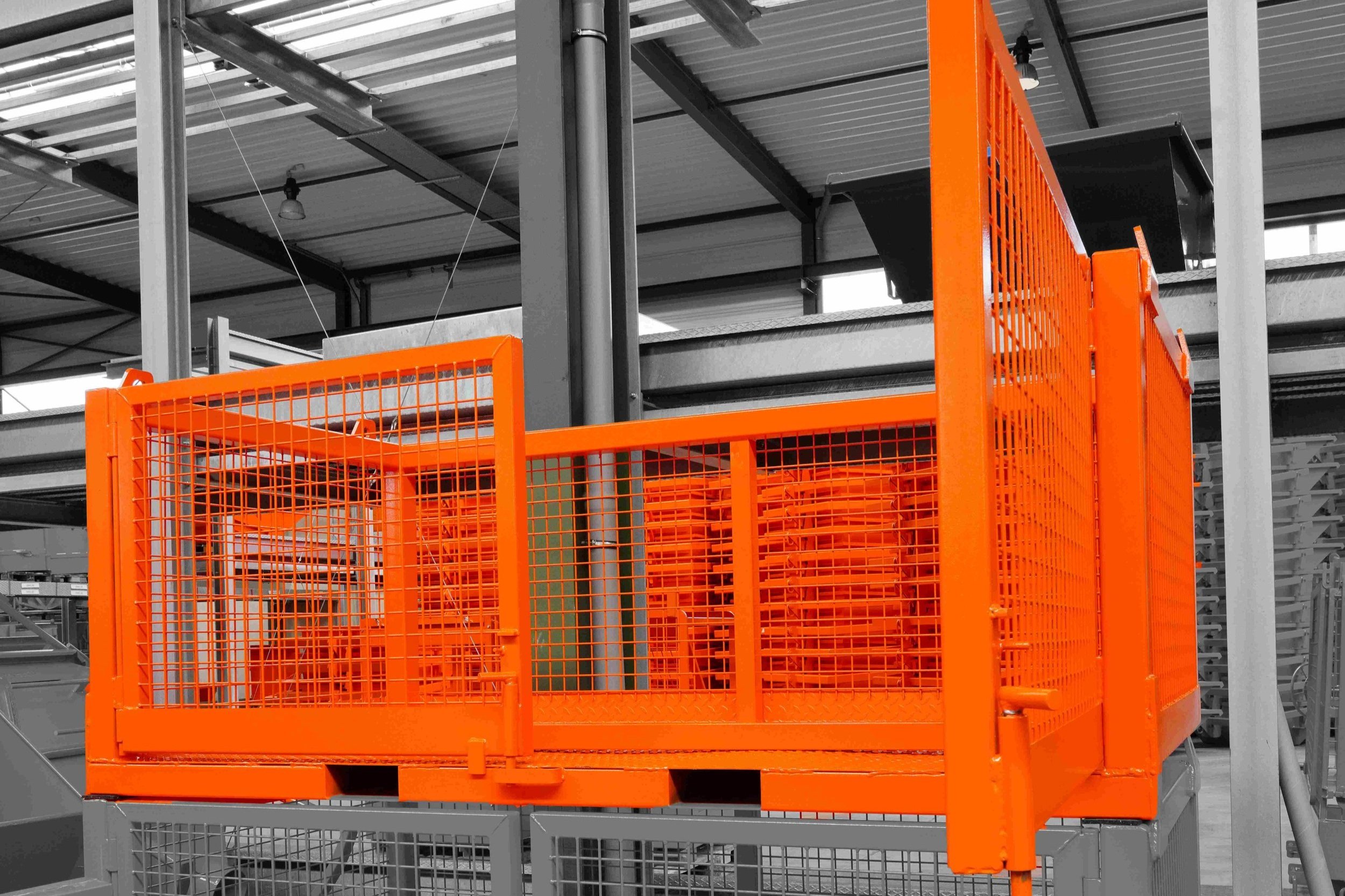 Crane Pallet Bin for two pallets. The bin is orange and in the factory with the factory background desaturated. These are sold by CraneGear.net in North America