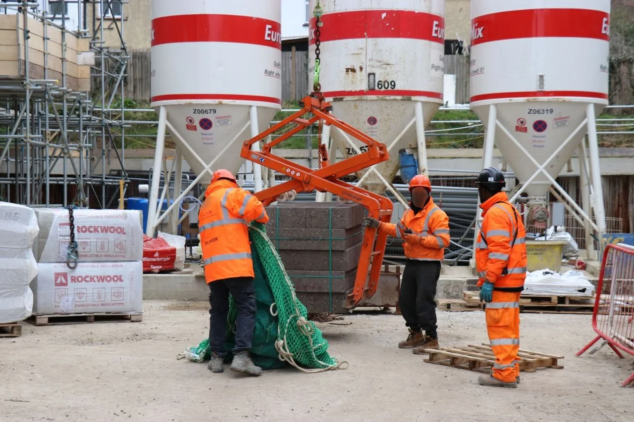 Eichinger 1083 Block clamp lifting blocks. There are people installing a net system to ensure everyone can be safe while working with the large pallet clamp.