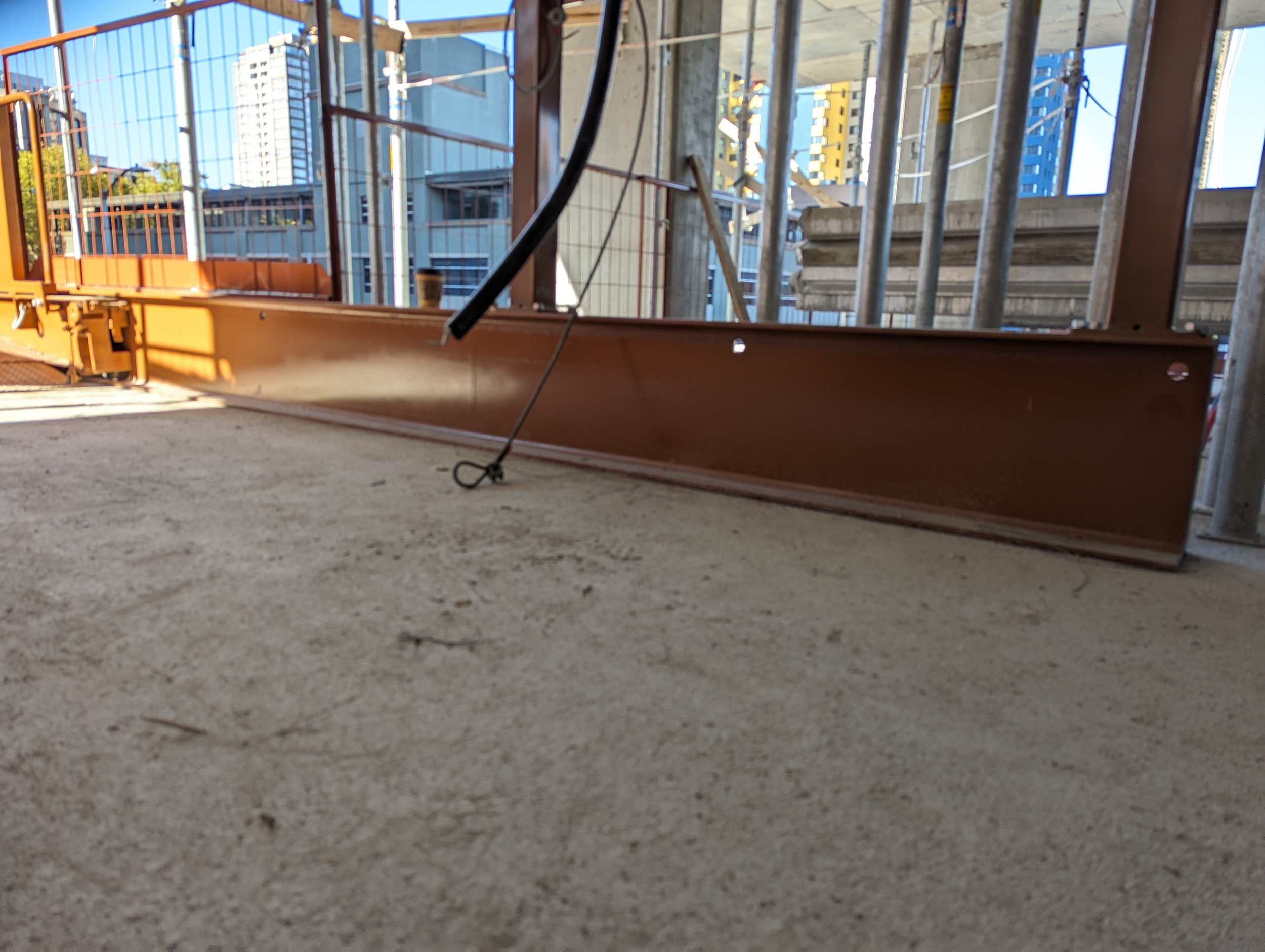Beam of a crane loading platform by Eichinger powder coated in Largo Concrete brown. It is on a concrete floor on an active construction site.