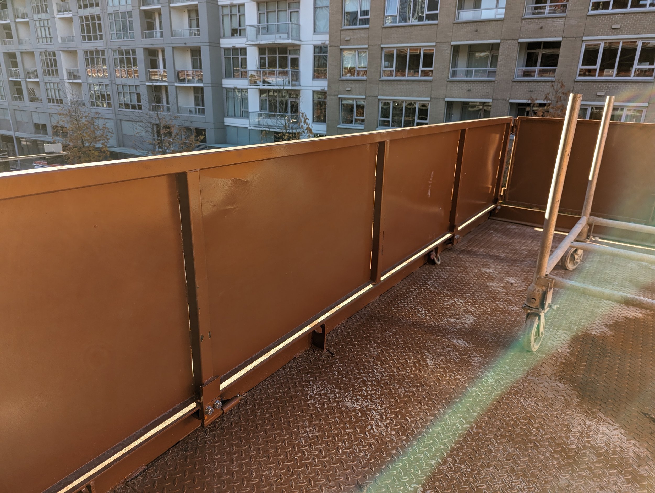 Crane Loading Platform Safety enclosure. This shows the height of the side panels and the protection provided. The color is Largo Brown with the city in the background