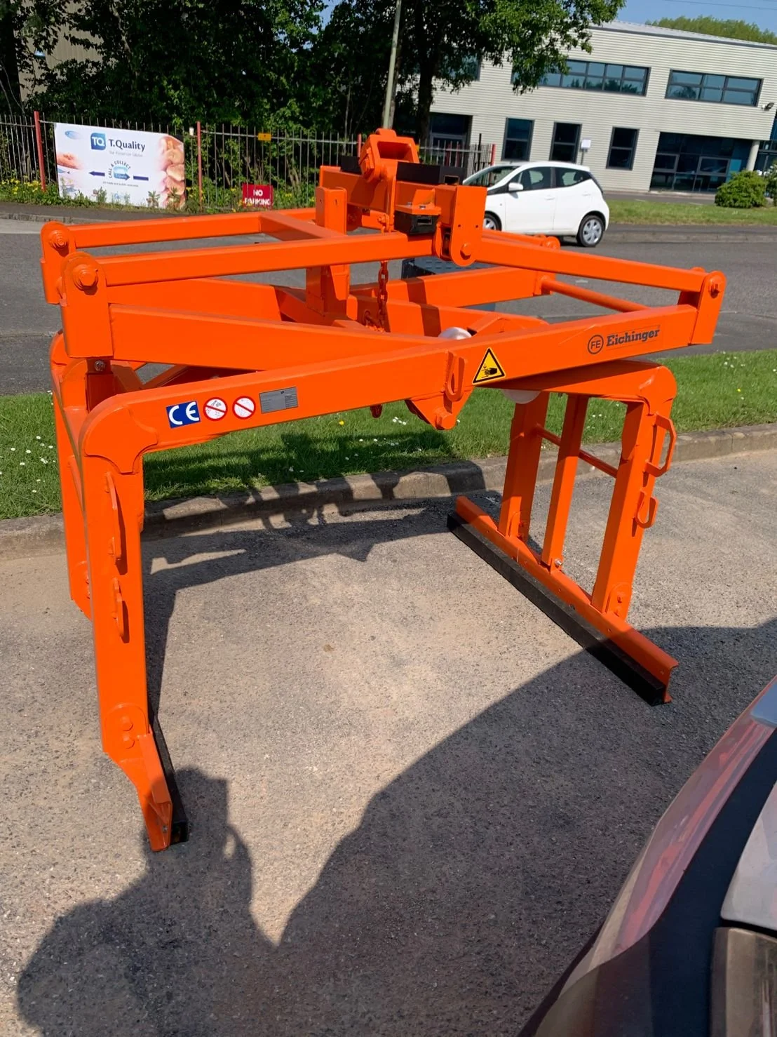 Eichinger's 1083 Pallet clamp in orange against a natural green grass background