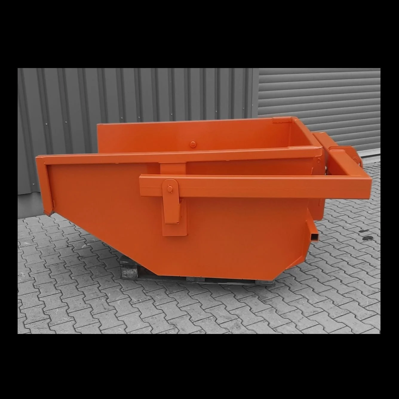 Eichinger skip boxes in orange as a profile shot on black and white background at the factory.